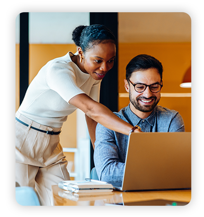 Business Internet Two excited coworkers work on laptop in modern office