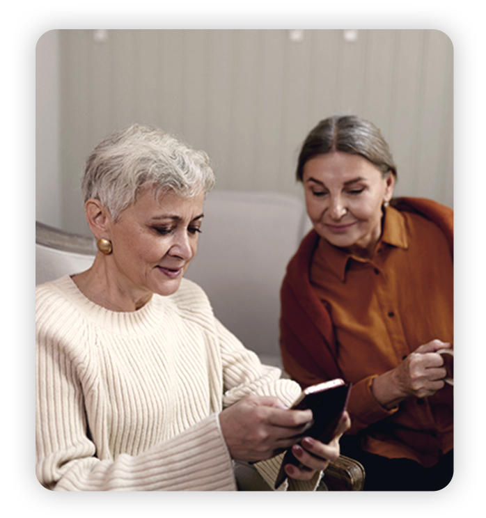 Refer a Friend Two mature women use phones together
